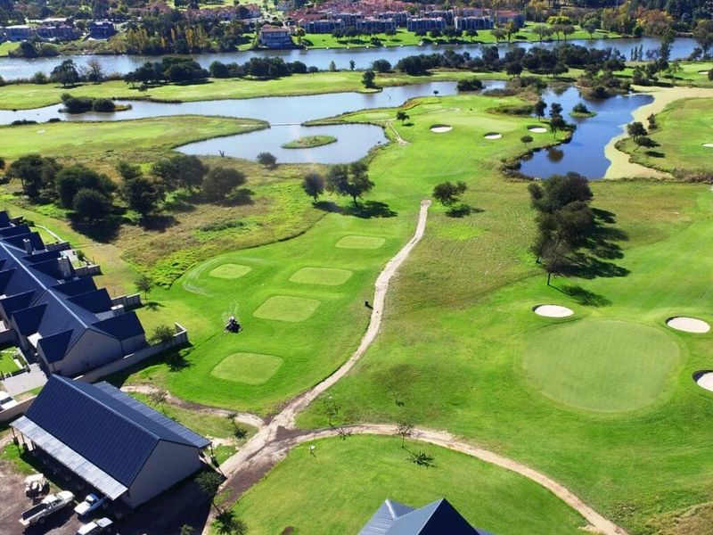 An aerial view of a residential property situated adjacent to a golf course with scenic water features and surrounding landscape.