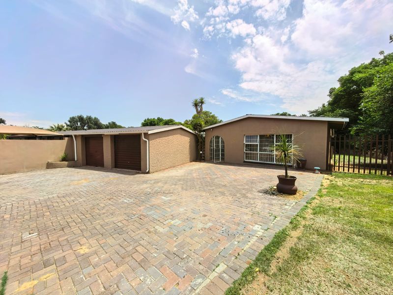 Front exterior view of the property featuring a paved driveway, double garage, and secure gated entrance.