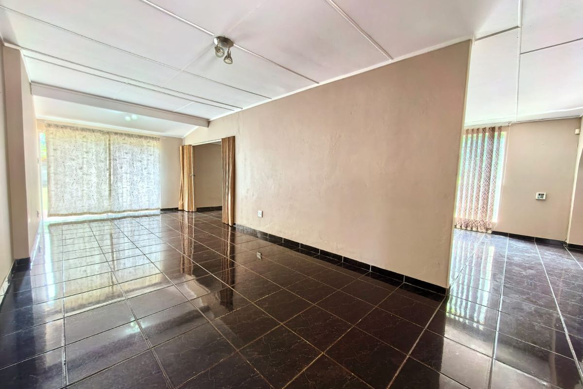 A spacious, empty living area featuring dark tiled flooring and neutral walls, offering a blank canvas for interior design and personalization.