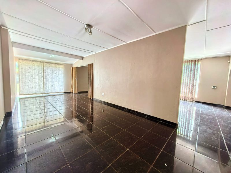 A spacious, empty living area featuring dark tiled flooring and neutral walls, offering a blank canvas for interior design and personalization.