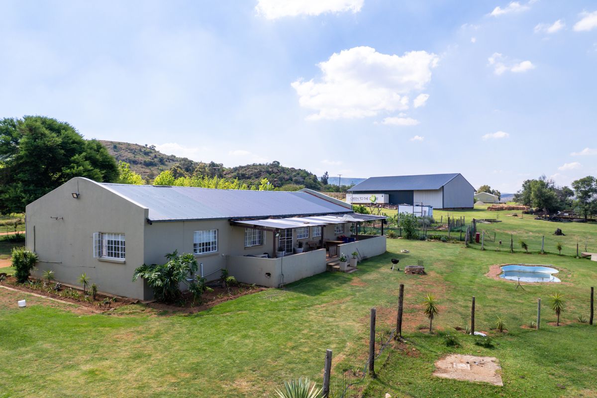 Aerial view of the rear farm property featuring a dwelling with a covered patio, a swimming pool, and a large detached storage shed.