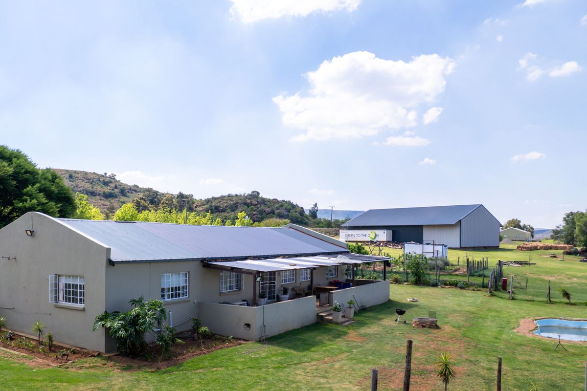 Aerial view of a farm property featuring a main residence with a patio, a swimming pool, and a large detached agricultural shed.