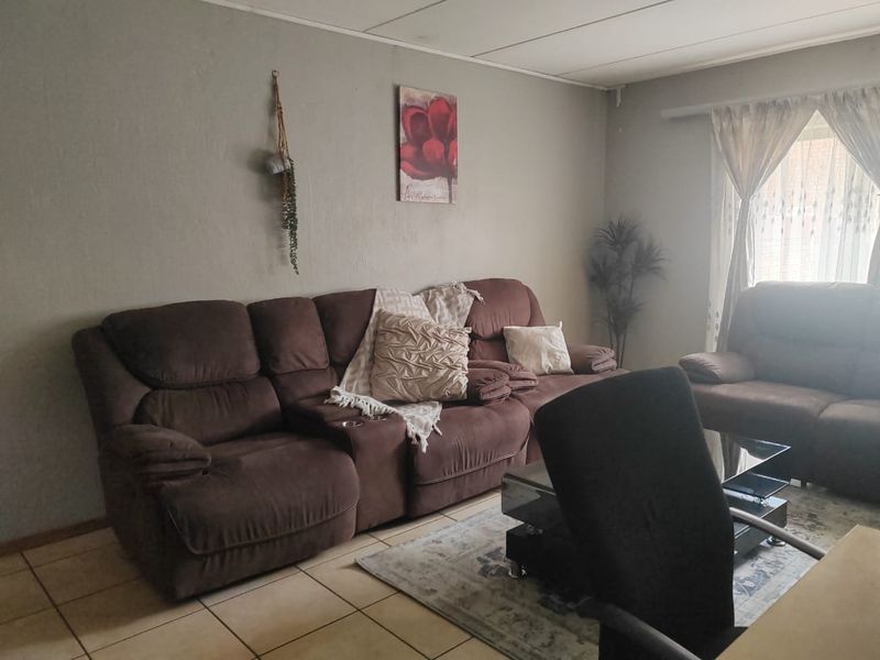 A living room featuring tiled flooring and a drop ceiling, offering a functional space that could benefit from cosmetic updates.