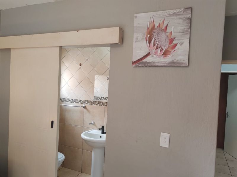 A bathroom featuring a pedestal basin and tiled walls, accessed via a sliding door from the adjacent living area.