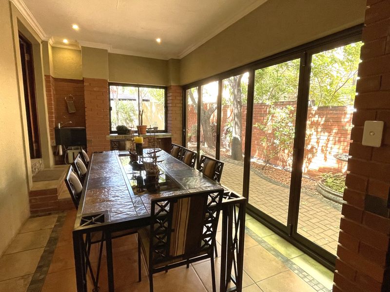 Spacious enclosed patio featuring exposed brick walls, tiled flooring, and large sliding glass doors that open to the garden area.