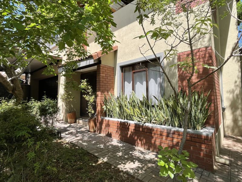 Front entrance view of the house featuring a brick facade, paved walkway, and a built-in brick planter box.