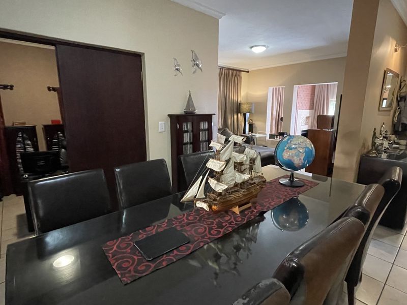 A dining area featuring tiled flooring and coving, with an open-plan layout connecting to adjacent living spaces.