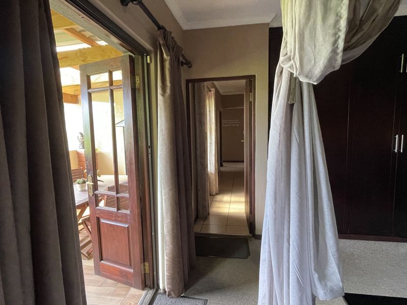 Bedroom featuring built-in cupboards, tiled flooring, and direct access to an outdoor patio area through a timber-framed glass door.