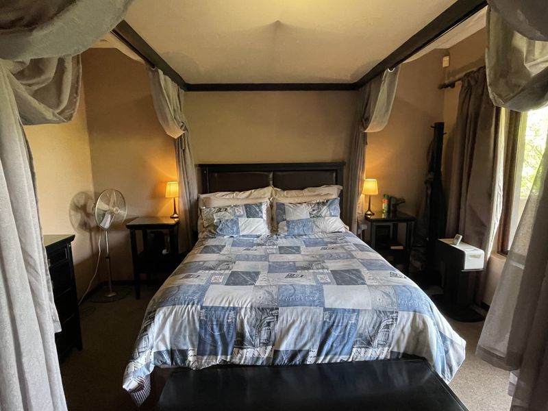 A bedroom featuring a four-poster bed frame and carpeted flooring, offering a cozy and traditional atmosphere.