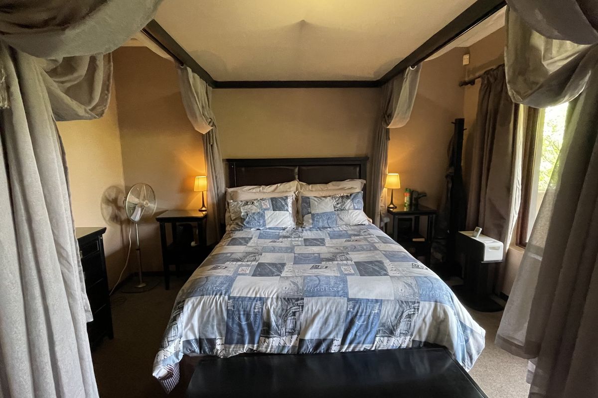 A bedroom featuring a four-poster bed frame and carpeted flooring, offering a cozy and traditional atmosphere.