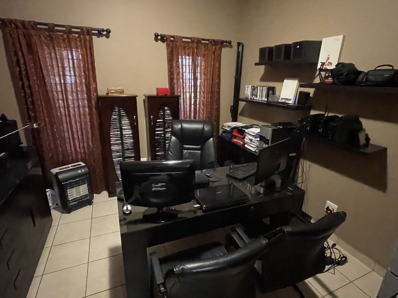 A functional home office space featuring tiled flooring and built-in wall shelving, providing a dedicated area for work or study.
