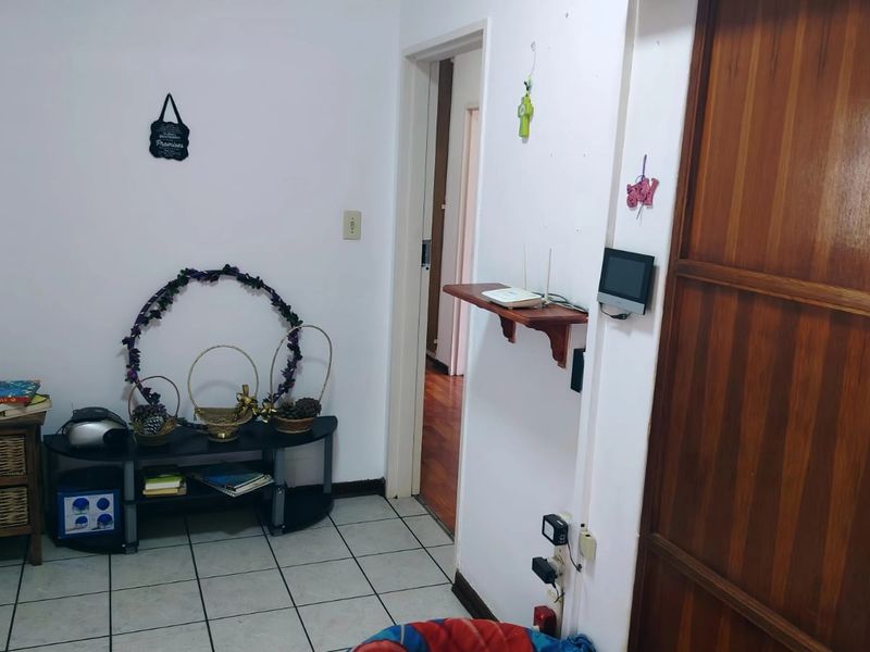 A functional hallway area featuring tiled flooring, a wooden door, and a wall-mounted intercom system, providing access to adjacent rooms.