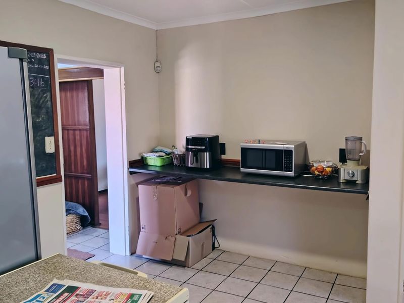 A functional kitchen area featuring tiled flooring, a built-in countertop, and access to adjacent rooms, providing a practical space for daily food preparation.