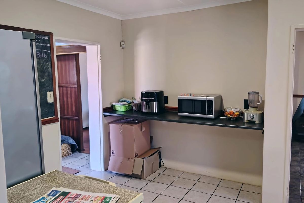 A functional kitchen area featuring tiled flooring, a built-in countertop, and access to adjacent rooms, providing a practical space for daily food preparation.