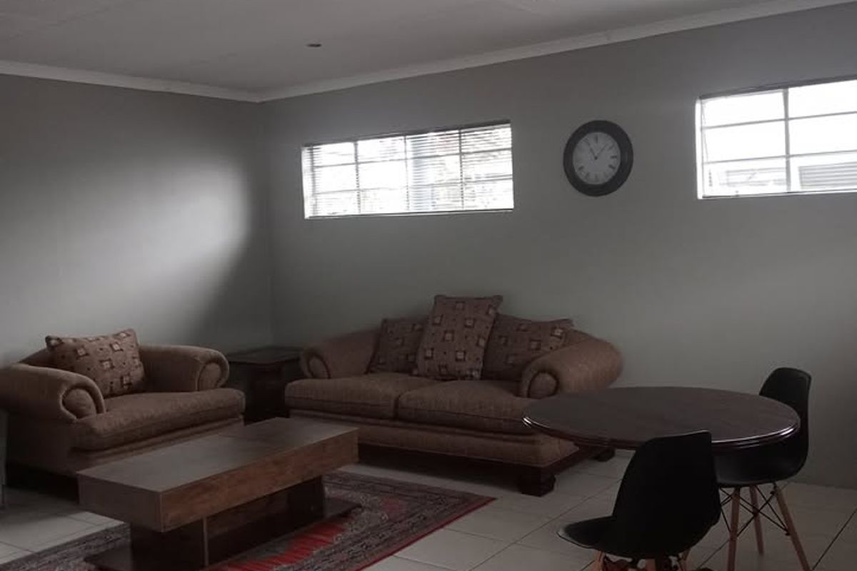 A spacious living area featuring neutral grey walls, tiled flooring, and recessed downlighting, offering a versatile space for relaxation and dining.