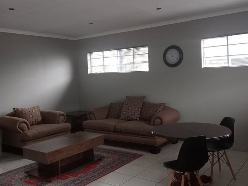 A spacious living area featuring neutral grey walls, tiled flooring, and recessed downlighting, offering a versatile space for relaxation and dining.