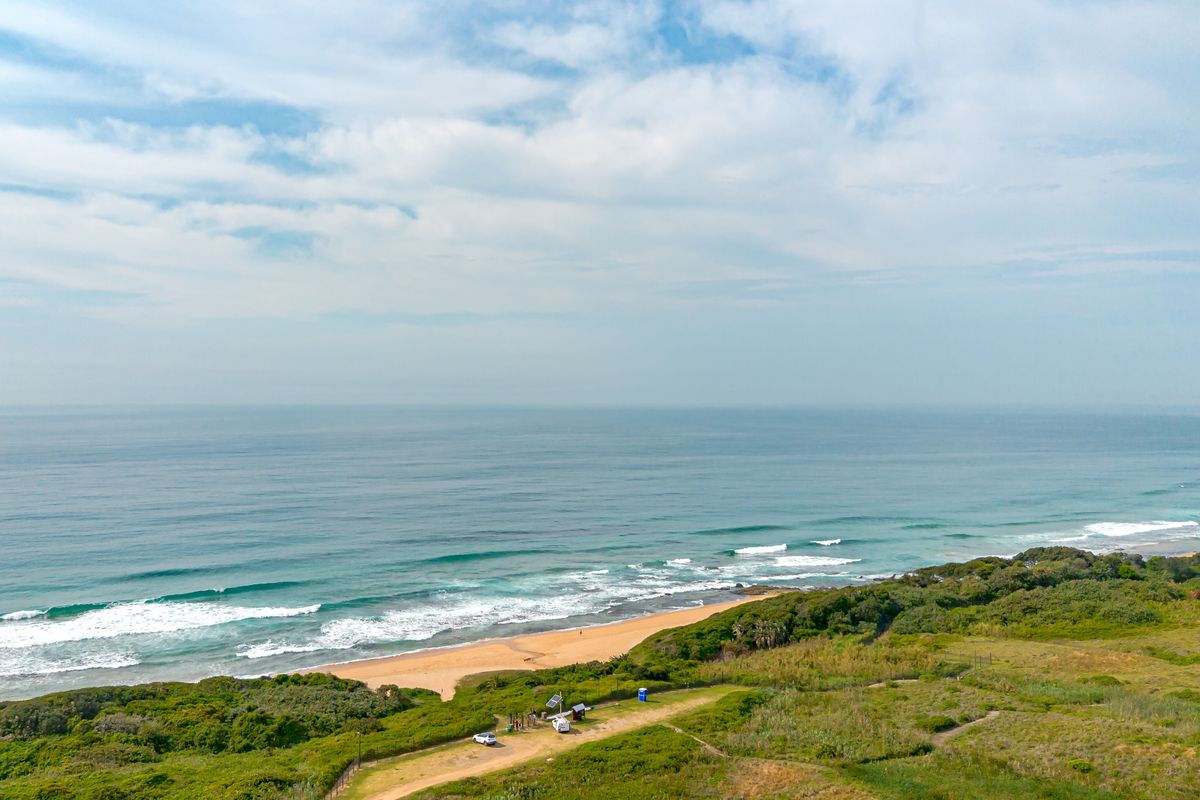 An aerial view of the coastal property, showcasing direct beach access, natural vegetation, and expansive ocean views.