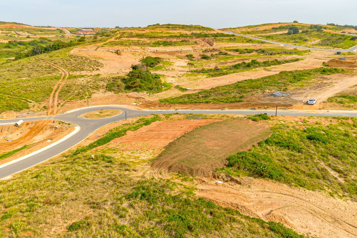 Aerial view of an undeveloped residential estate featuring paved roads, a roundabout, and cleared plots ready for construction.