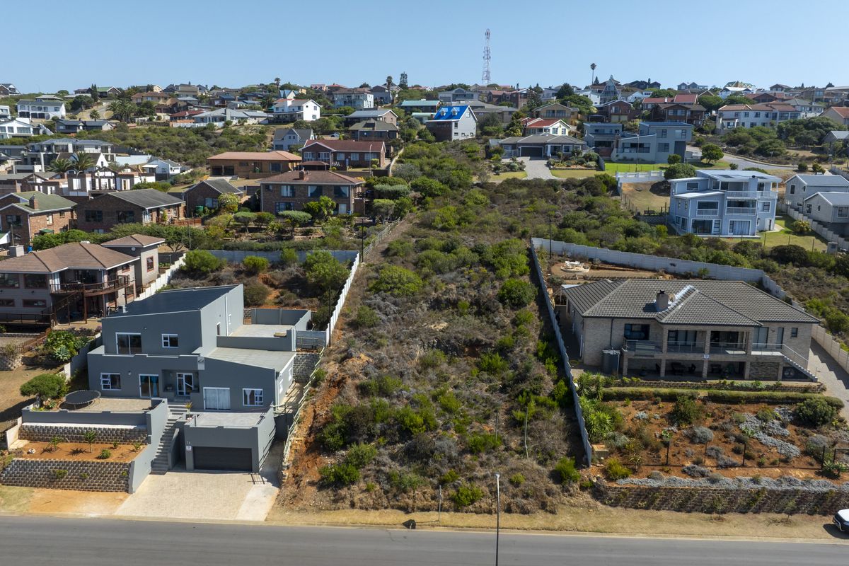 Aerial view of a vacant residential plot situated between two existing developed properties in a suburban coastal neighborhood.