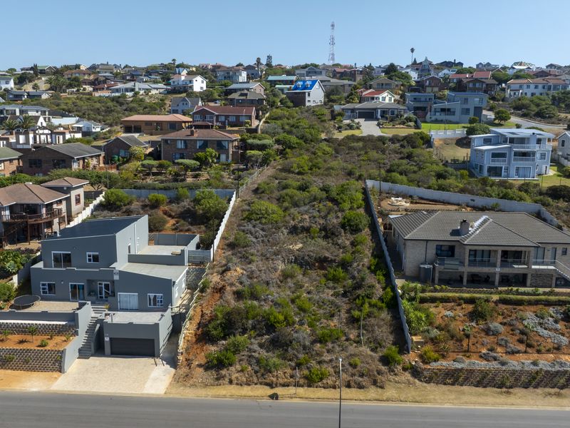 Aerial view of a vacant residential plot situated between two existing developed properties in a suburban coastal neighborhood.