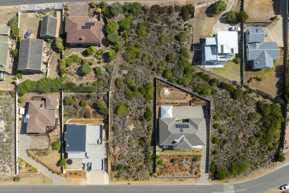 An aerial view of a vacant residential plot situated within an established neighborhood, showcasing the surrounding properties and land layout.