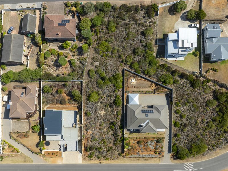 An aerial view of a vacant residential plot situated within an established neighborhood, showcasing the surrounding properties and land layout.