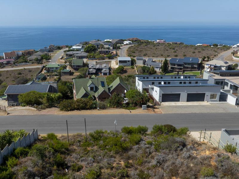 Aerial view of a vacant residential plot situated in a coastal neighborhood, featuring established road access and surrounding residential development.