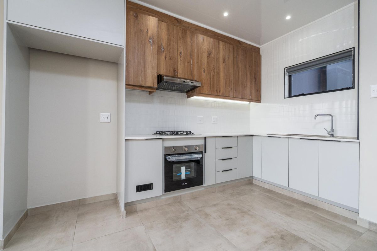 Modern kitchen featuring wood-look upper cabinets, sleek white lower cabinetry, built-in oven, gas hob, and tiled flooring in a clean, contemporary finish.