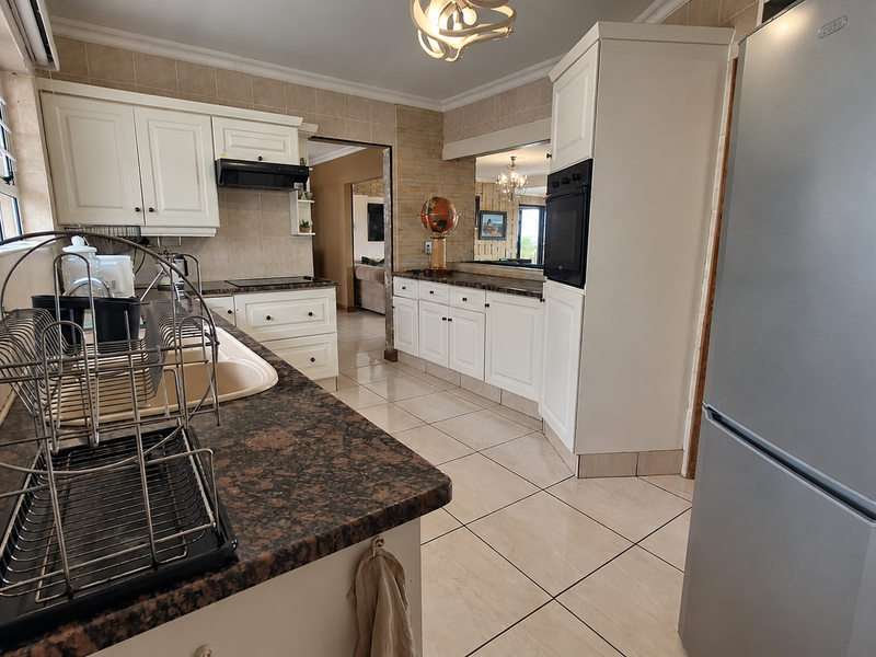 A well-maintained kitchen featuring white cabinetry, granite countertops, tiled flooring, and built-in appliances, offering a functional and classic cooking space.