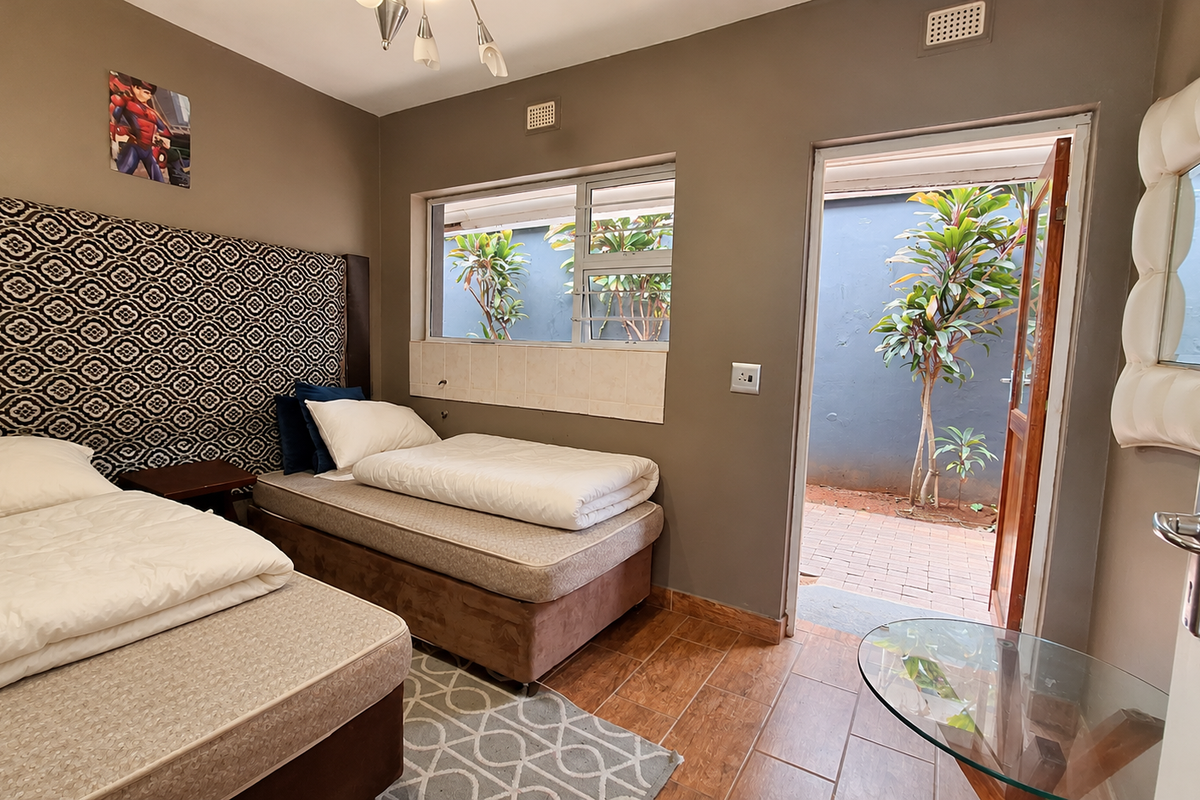 A bedroom featuring tiled flooring, an aluminium window, and direct access to an outdoor patio area.