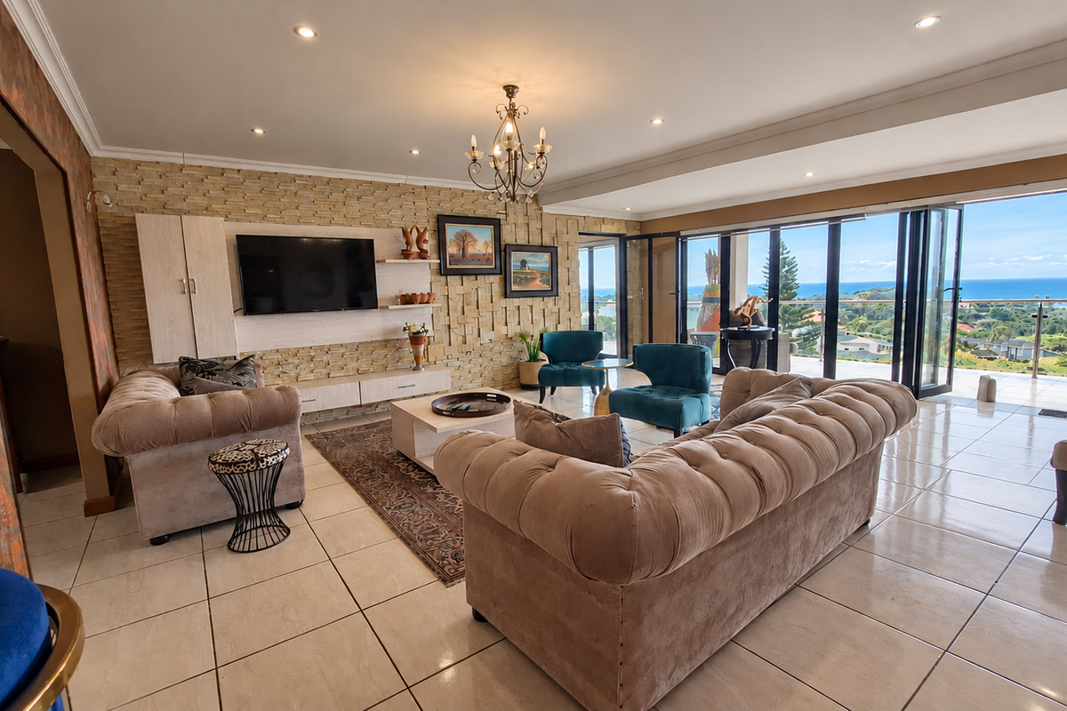 Spacious living room featuring a textured stone accent wall, tiled floors, and large bi-fold doors opening to a scenic coastal view.