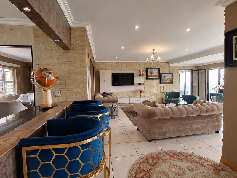 Spacious open-plan living area featuring stone-clad feature walls, tiled flooring, recessed lighting, and a breakfast bar connecting to the kitchen space.