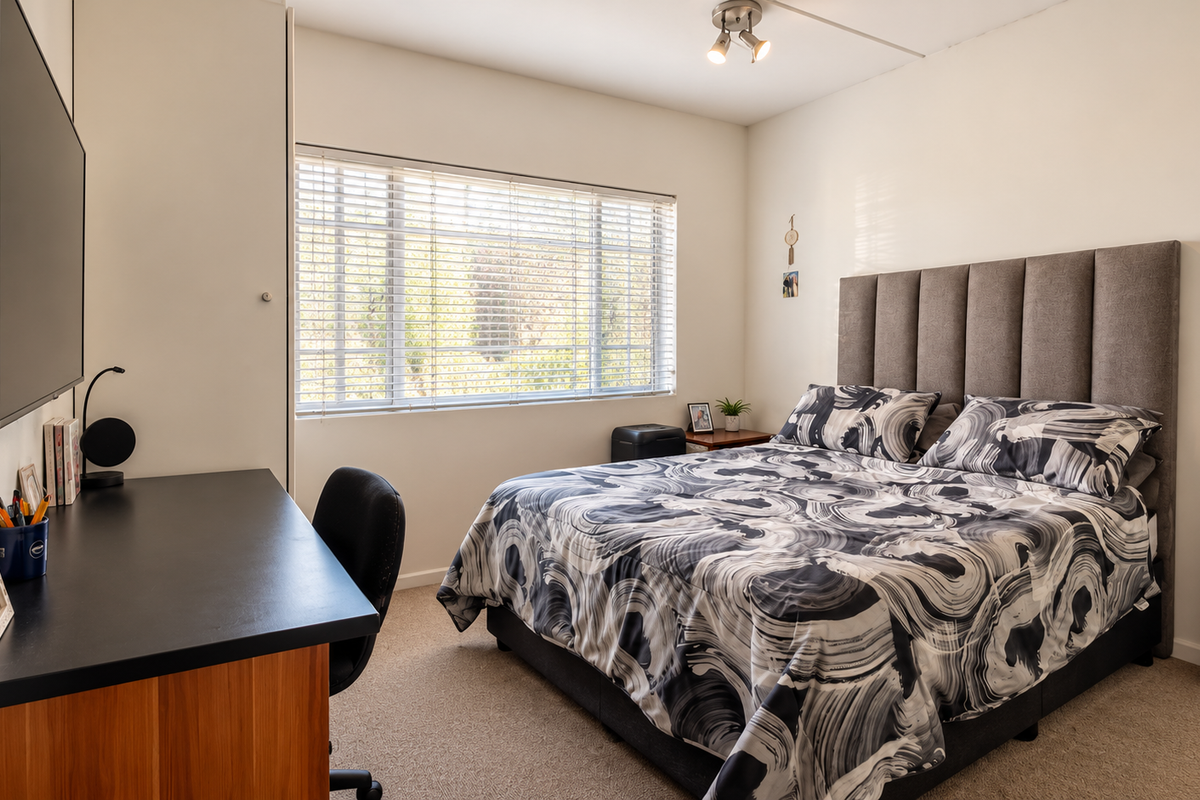 A well-maintained bedroom featuring neutral walls, carpet flooring, a built-in wardrobe, and venetian blinds allowing natural light.