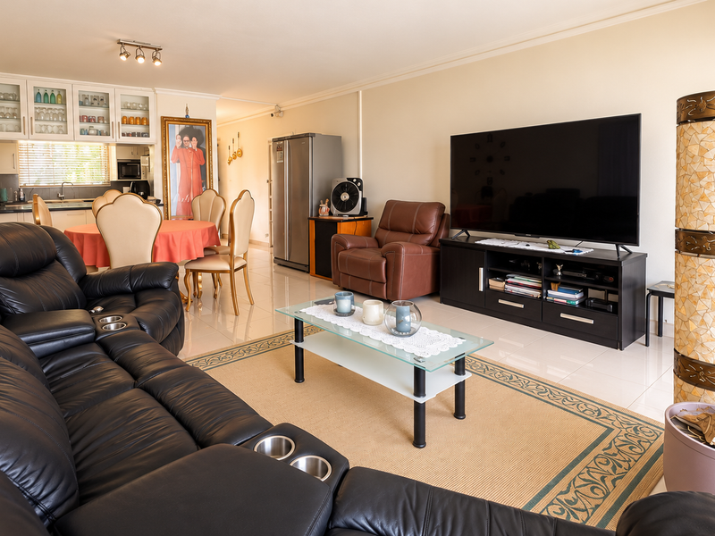 Spacious open-plan living and dining area featuring tiled flooring, integrated kitchen cabinetry, and neutral wall finishes, creating a functional and cohesive living space.