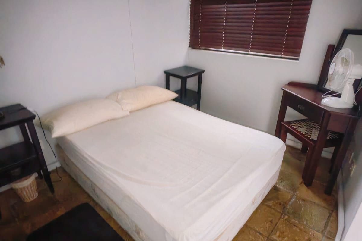 A bedroom featuring tiled flooring and venetian blinds, providing a functional space with natural light.