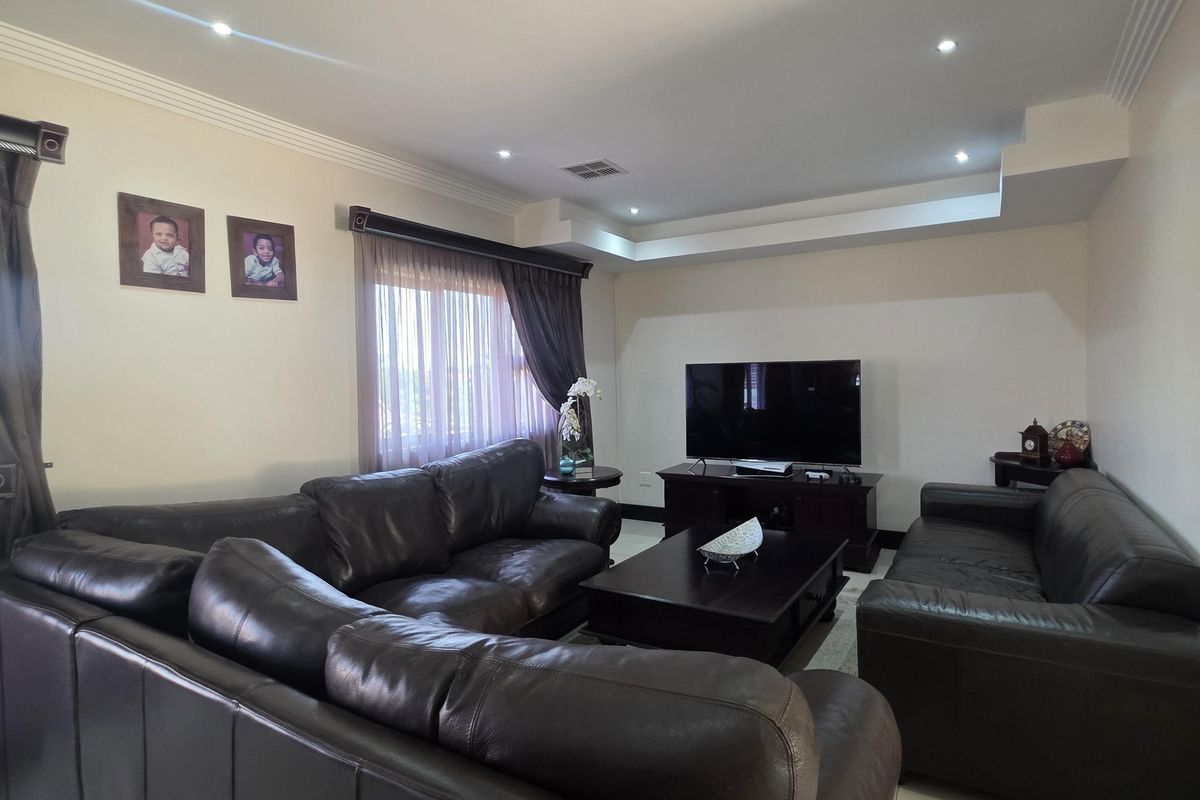 A spacious living room featuring tiled flooring, recessed ceiling lighting, and a decorative cove ceiling, providing a comfortable and well-lit area for relaxation.