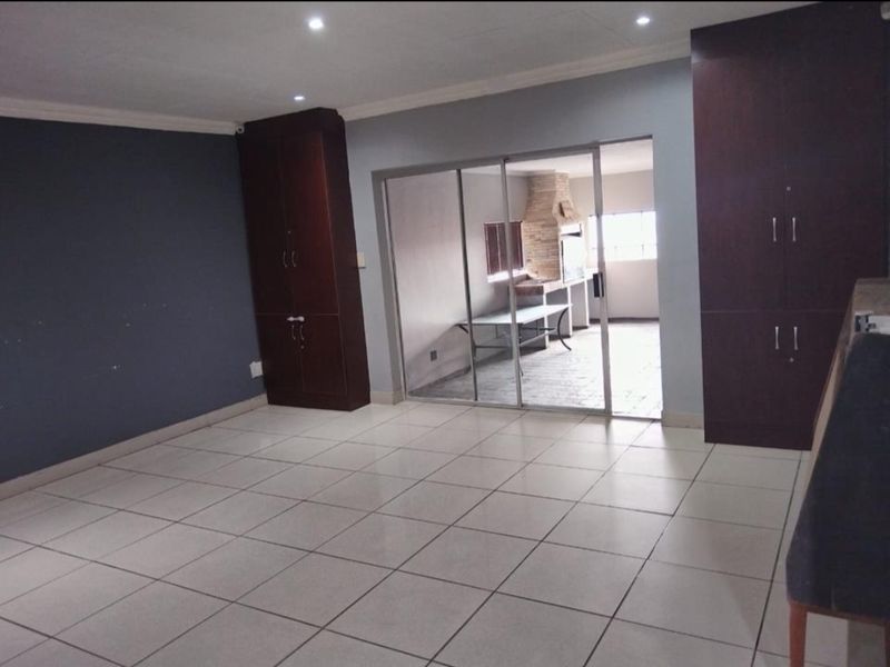 Spacious living area featuring tiled flooring, built-in storage cupboards, and sliding glass doors leading to an outdoor patio area.