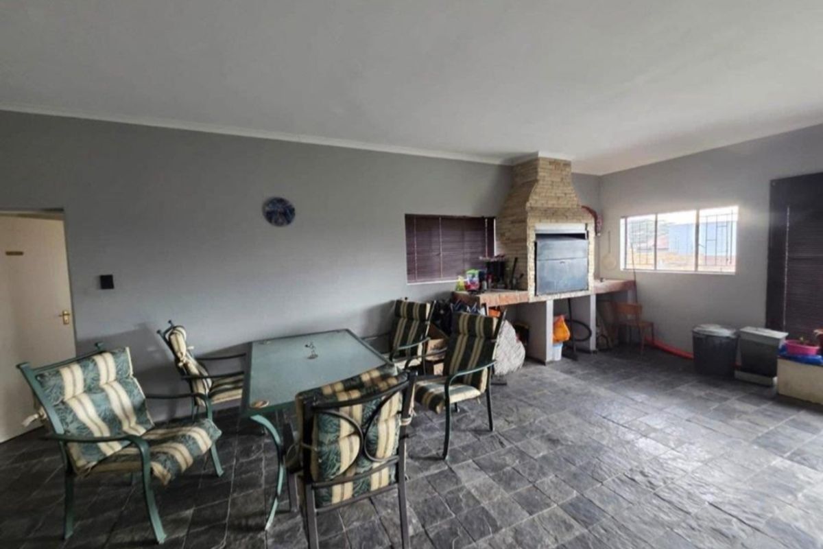 Covered patio area featuring stone tile flooring and a built-in brick braai, providing a functional space for outdoor entertaining.