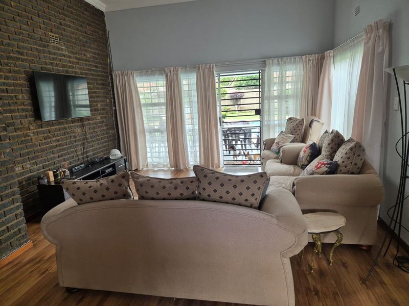 A comfortable living room featuring an exposed brick accent wall, laminate flooring, and direct access to the outdoor area through a sliding glass door.
