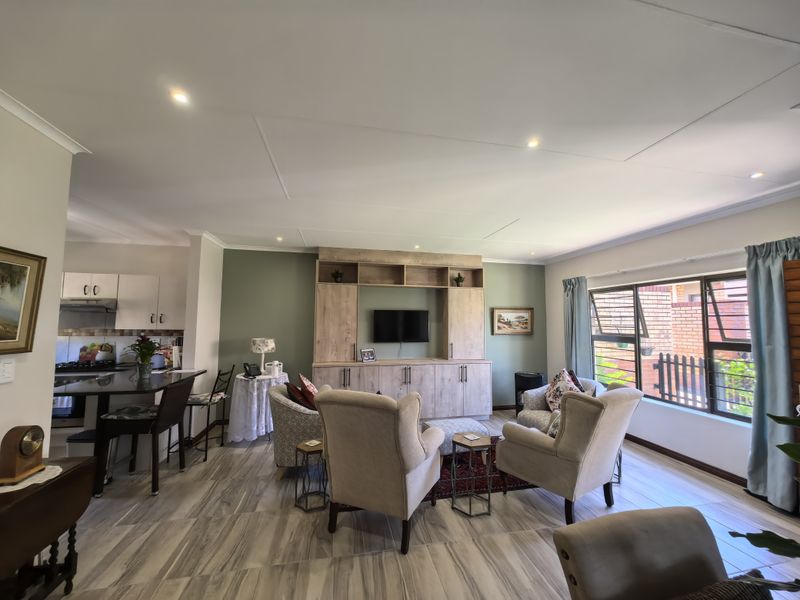 Spacious open-plan living area featuring a modern kitchen with island, built-in cabinetry, and large windows providing ample natural light.