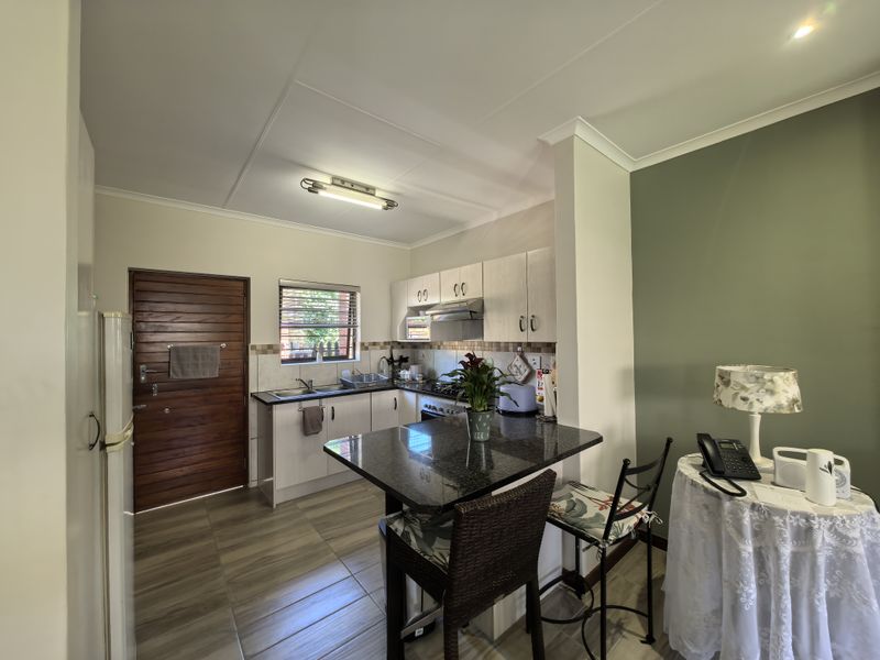 Compact kitchen featuring built-in cabinetry, granite countertops, integrated appliances, and a breakfast bar, finished with tiled flooring and neutral wall tones.