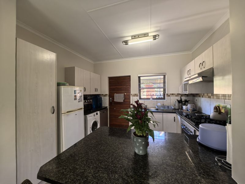 Functional kitchen featuring granite countertops, built-in cabinetry, a tiled backsplash, and integrated cooking appliances, offering a practical layout for daily meal preparation.