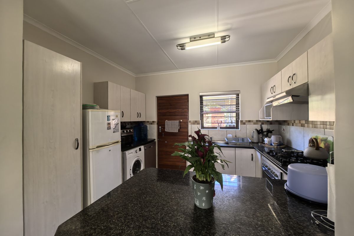Functional kitchen featuring granite countertops, built-in cabinetry, a tiled backsplash, and integrated cooking appliances, offering a practical layout for daily meal preparation.