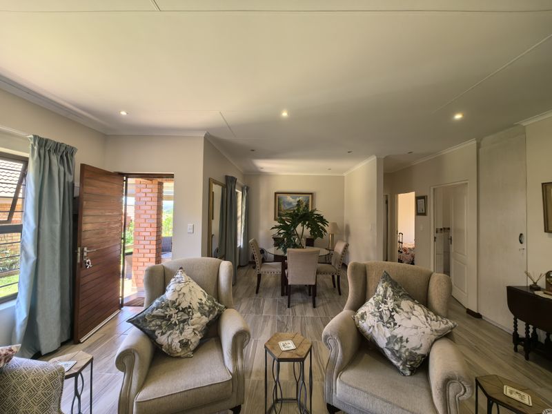 Spacious open-plan living and dining area featuring neutral tiled flooring, recessed lighting, and direct access to an outdoor patio through a timber door.