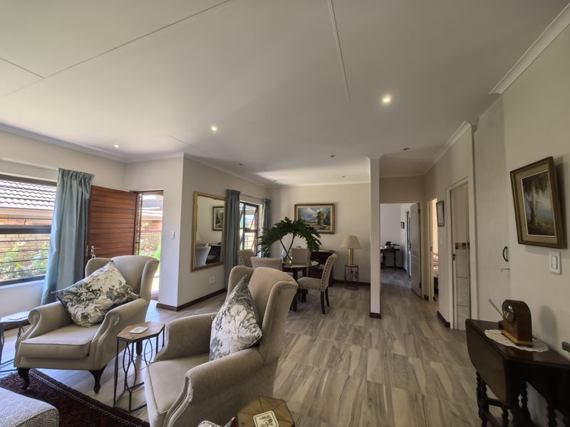 Spacious open-plan living and dining area featuring modern tiled flooring, recessed downlighting, and direct access to the exterior through a timber entrance door.