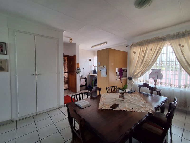 Open plan dining area with tiled flooring and adjacent kitchen space featuring built-in cabinetry and stove.