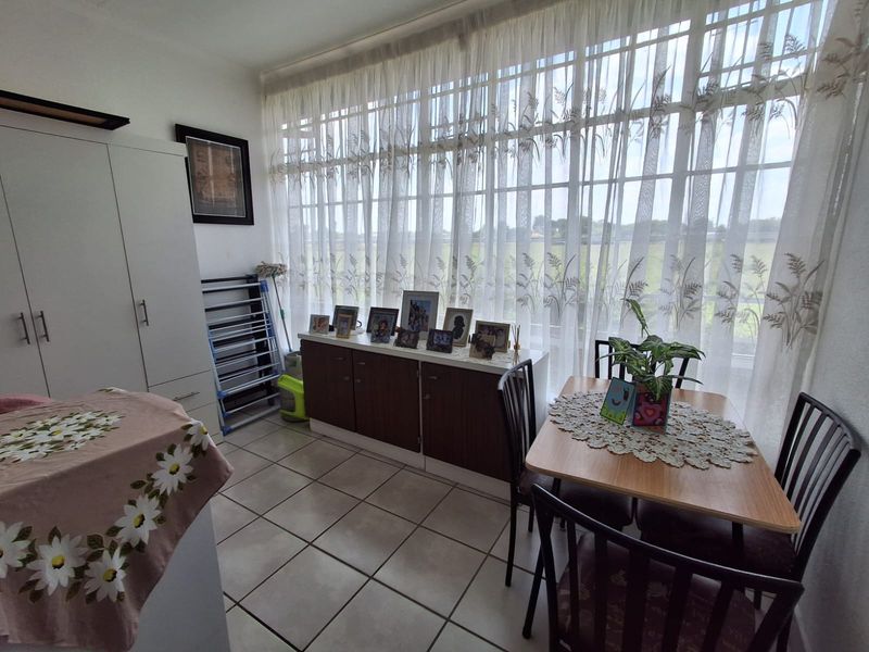 A bright living area featuring large floor-to-ceiling windows, tiled flooring, and a built-in wardrobe, offering a functional and well-lit space.
