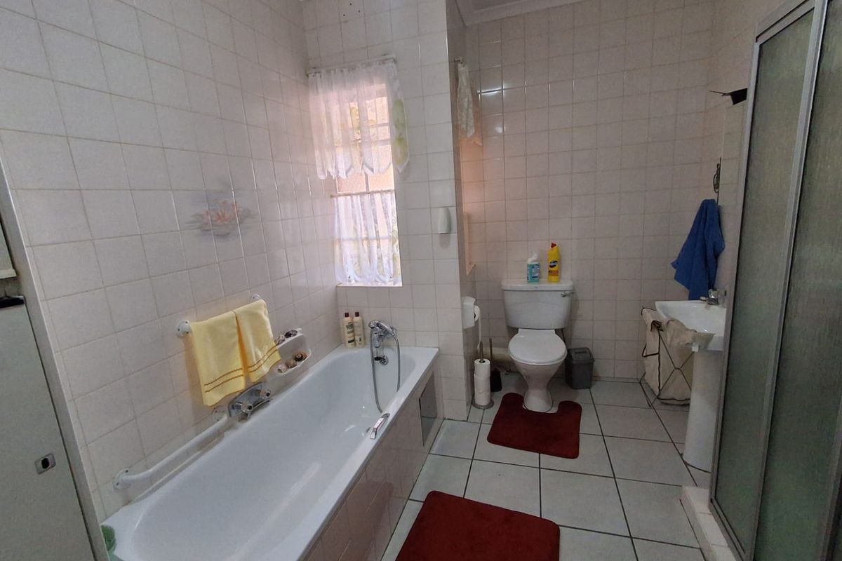 A functional bathroom featuring a bathtub, pedestal basin, toilet, and separate shower enclosure with full-height wall tiling.