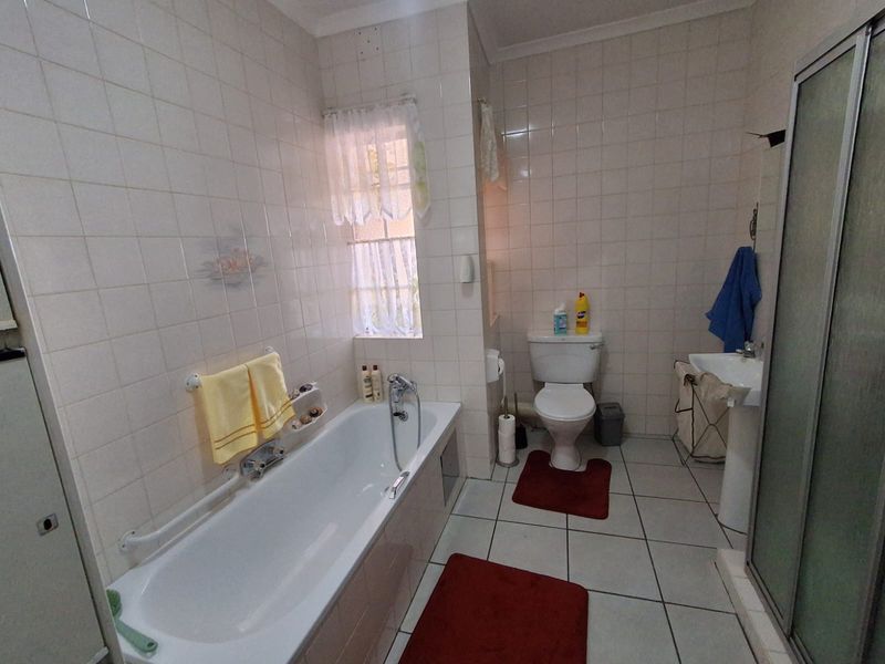 A functional bathroom featuring a bathtub, pedestal basin, toilet, and separate shower enclosure with full-height wall tiling.