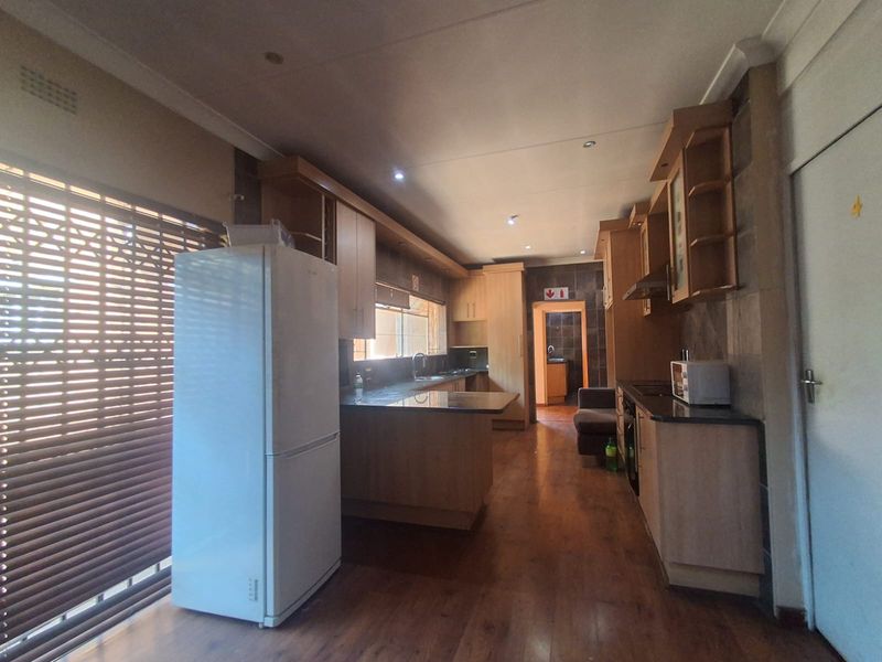A functional kitchen featuring wooden cabinetry, granite countertops, and integrated lighting, with a seamless flow into the adjacent living area.